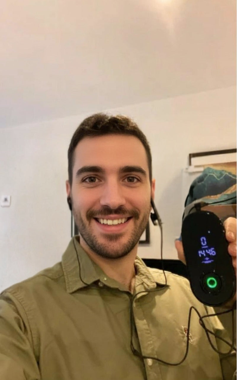 NeuroRest-Man holding a device with a digital display in a room.