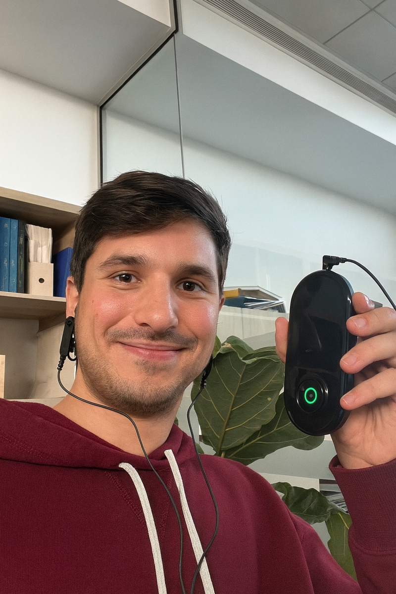 NeuroRest-Person holding a black electronic device with a green light in an indoor setting.