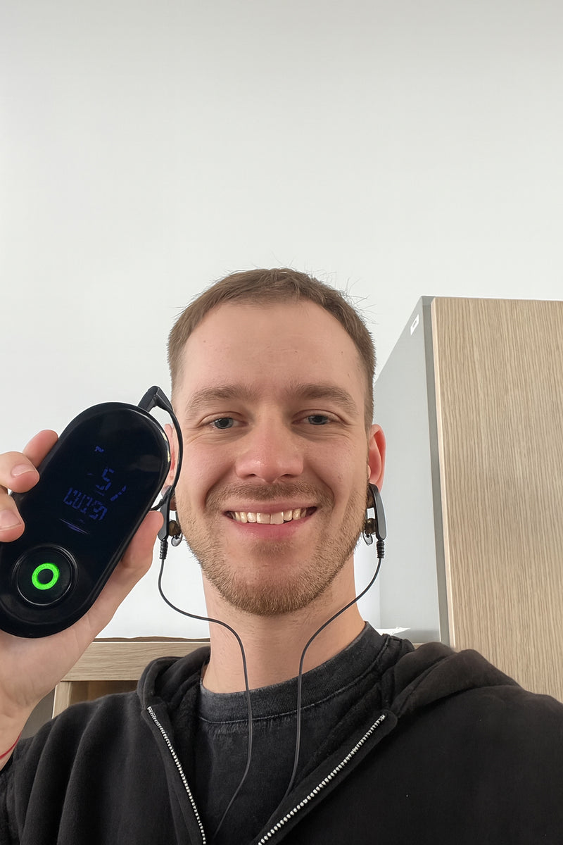 NeuroRest-Man holding a digital device with a screen, smiling indoors.